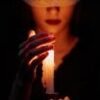 A blindfolded woman holding a lit candle in a dark setting, invoking mystery.